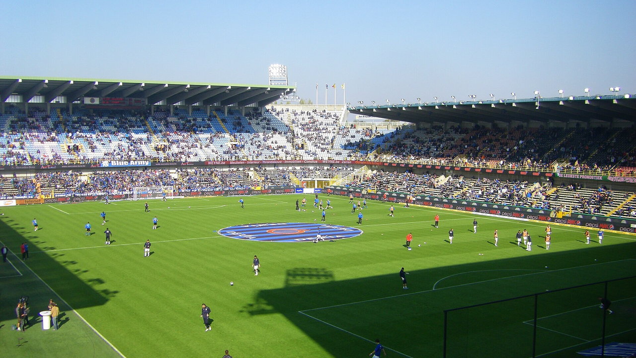 Jan Breydel Stadion in Brügge — Innenraum bei Tageslicht während eines Spiels, blaue Sitzreihen auf den Rängen