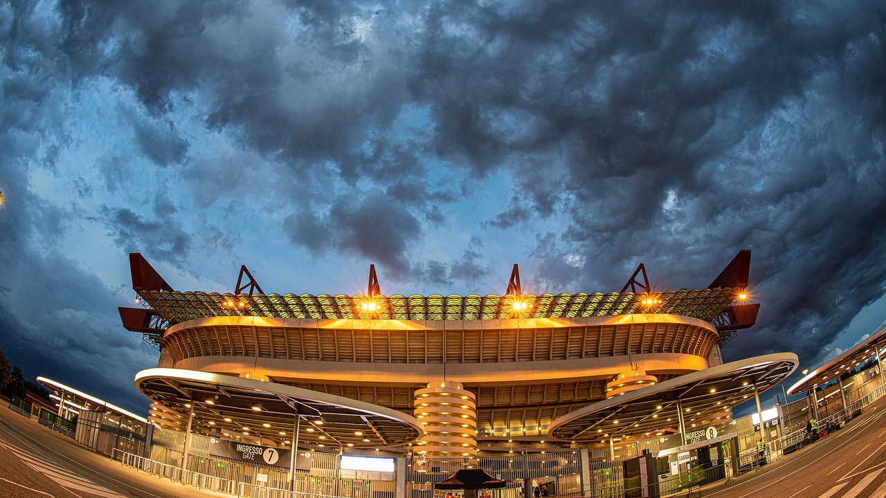 San Siro in Mailand — Aussenansicht in der Dämmerung, die runden Rampentürme beleuchtet unter einem Wolkenhimmel