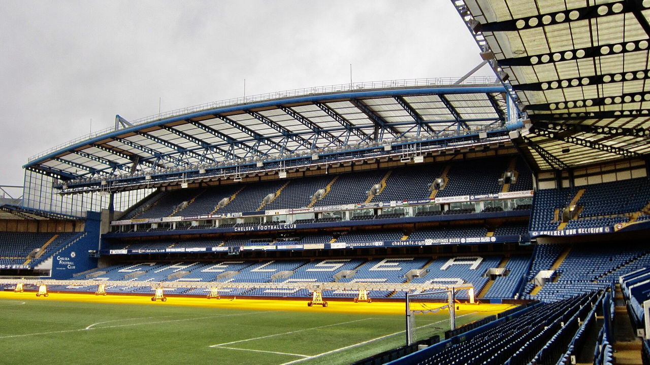 Stamford Bridge in London — Innenraum mit blauen Sitzreihen und der überdachten Tribüne über dem Rasen